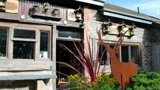 Silhouet van een hert, symbool van de Belgische Ardennen, voor de stenen gevel van restaurant La Petite Fontaine in Achouffe