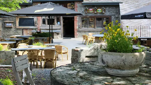 Ingang en schaduwrijk terras van La Petite Fontaine in Achouffe