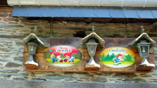 Enseignes Cherry Chouffe et Mc Chouffe sur le mur de pierres de schiste et de grès aux formes irrégulières de la façade de La Petite Fontaine à Achouffe