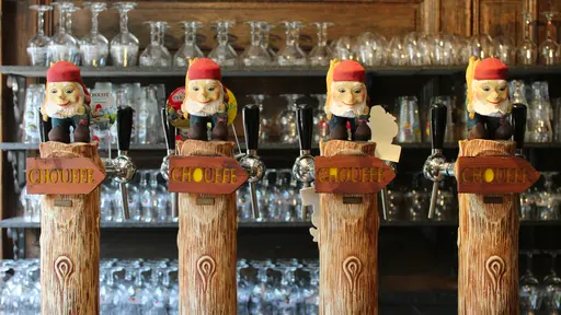 Quatre pompes à bière Chouffe sculptées en bois et surmontées de lutins Marcel au comptoir de La Petite Fontaine à Achouffe