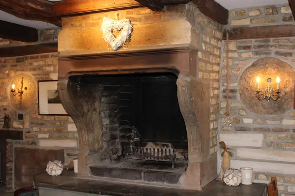Grande cheminée en pierre d'époque et murs en briques à l'intérieur du restaurant La Petite Fontaine